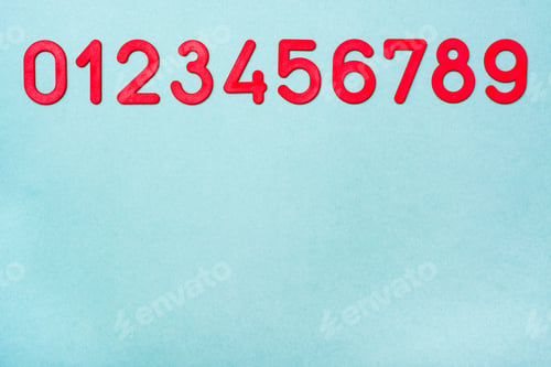 Preview: Red Plastic Numbers From Zero To Nine Lie In A Row On A Green Background. Top View. Copy Space