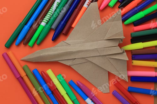 Preview: Origami Paper Airplane Mockup. Selective Focus. A Lot Of Multi-Colored Felt-Tip Pens On A Blurry