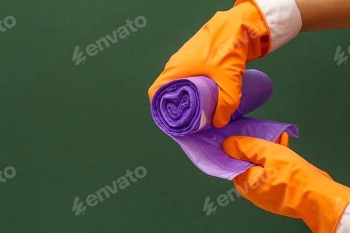 Preview: Women'S Hands In Orange Protective Glove With Garbage Bags On The Green Background. Washing And