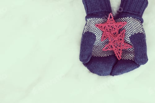 Preview: Woman Hands In Light Teal Knitted Mittens Are Holding Stars On Snow Background. Winter And