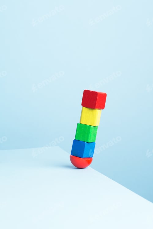 Preview: Colorful Wooden Cubes In Balance At The Edge Of The Table