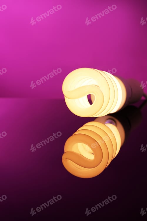 Preview: Glowing Spiral Light Bulb With Reflection On Color Table