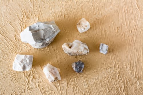 Preview: Various Natural Stones On A Textured Beige Plaster Background. Top View
