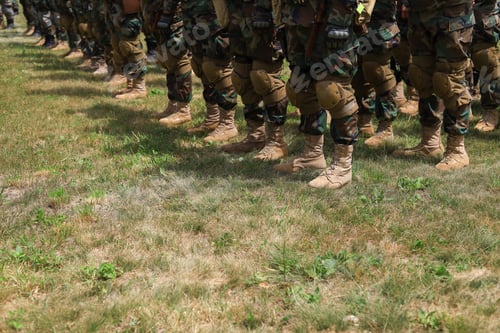 Preview: Legs Of Real Soldiers In Military Boots And Clothes Standing In Formation On The Grass. Background