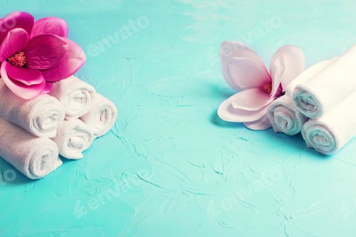 Preview: Massage And Wellness Layout. White Towels For Spa And Pink Flowers Of Magnolia On Blue Textured