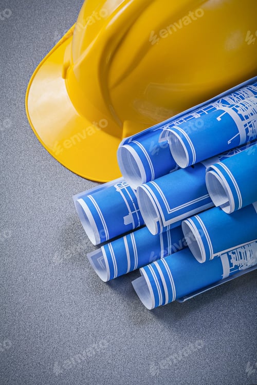 Preview: Yellow Hard Hat Blue Rolled Engineering Drawings On Grey Background Construction Concept.