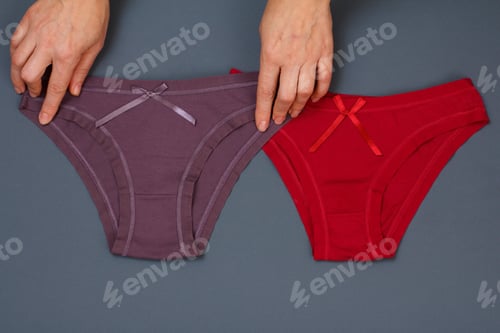 Preview: Women'S Hands Holding Brown Cotton Panties And Red One On Gray Background. Woman Underwear Set. Top