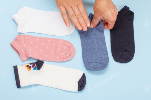 Preview: Female Hands With Women Socks On A Blue Background, Top View.