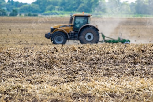 Preview: Fresh Tillage On The Field And A Defocufed Wheeled Tractor On The Background