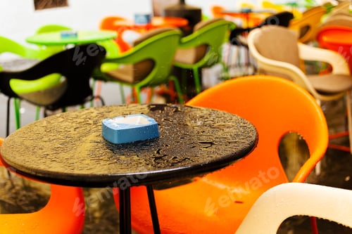 Preview: Wet Table With Blue Ashtray, Empty Tables And Seats In The Background; Note Shallow Depth Of Field
