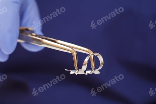 Preview: Close-Up View Of Dentist'S Hand In A Latex Glove With Dental Tongs And Clasp. Shallow Depth Of