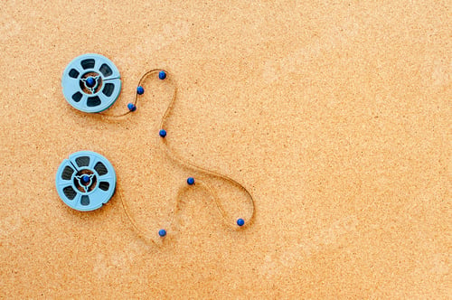 Preview: Two Little Blue Movie Reel Connected With Filmstrip Path On Wooden Cork Board