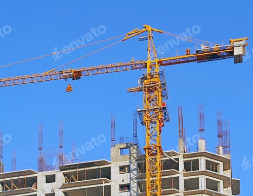 Preview: Building Crane And Building Under Construction Against Evening Blue Sky