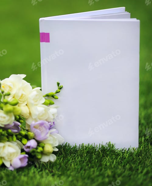 Preview: A Bouquet Of Freesias Lies On The Lawn Grass Next To A White Book. Place For Text. Template Of