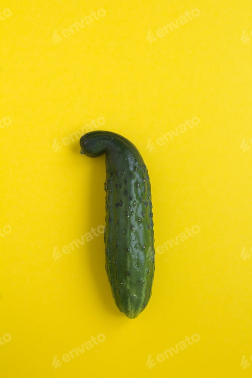 Preview: Ugly Food. Ugly Cucumber On The Yellow Background. Location Vertical. Top View. Copy Space.