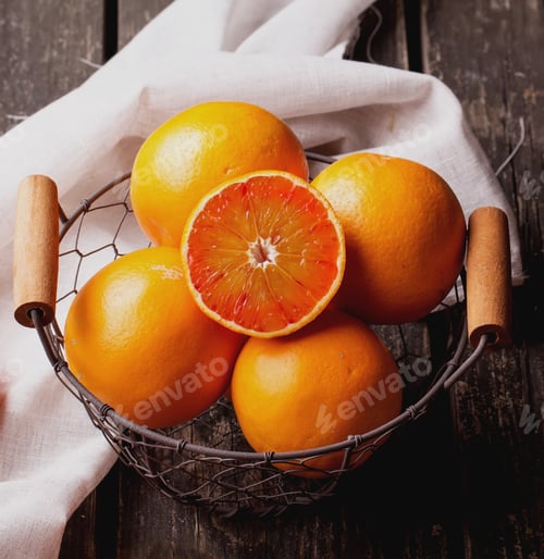 Preview: Bio Bloody Oranges And Lemons In The Basket On Rustic Wooden Board, Cut In Halves. Top View