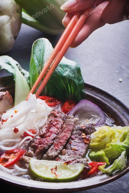 Preview: Vietnamese Pho Bo Soup Served In Vintage Oriental Bowl With Chop Sticks, Seasoning And Greens On