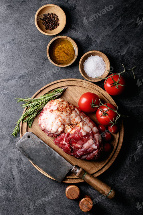 Preview: Raw Pork Meat On Wooden Round Board Served With Tomatoes, Salt, Pepper And Olive Oil Over Blue