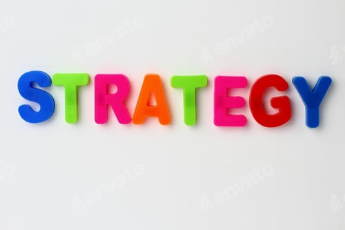 Preview: Text Made In Multicolored Magnetic Letters. Strategy. White Wooden Background.
