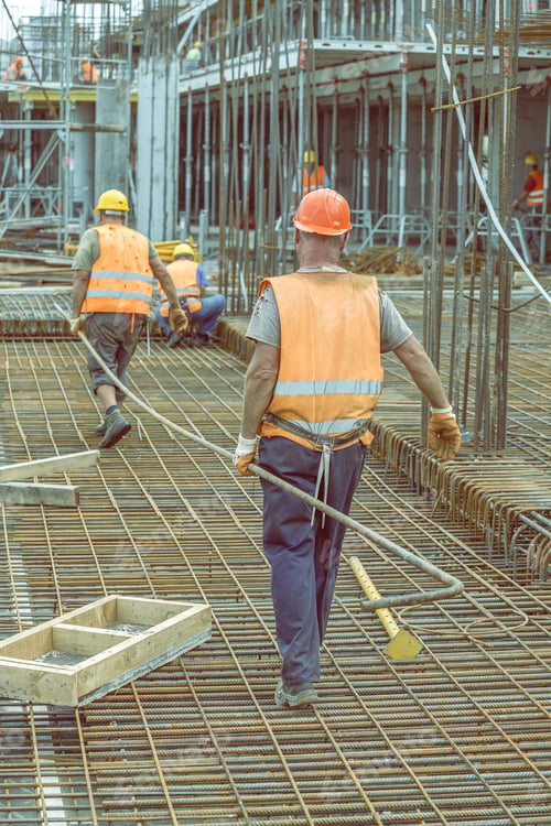Preview: Construction Workers Carrying Heavy Steel Bar At Construction Site. Selective Focus And Vintage