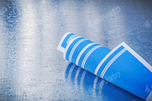 Preview: Blue Rolled Up Construction Plans On Scratched Metallic Background.