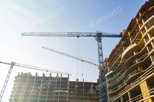 Preview: High Building Under Construction. Side With Cranes Against Blue Sky With Sun Glare.