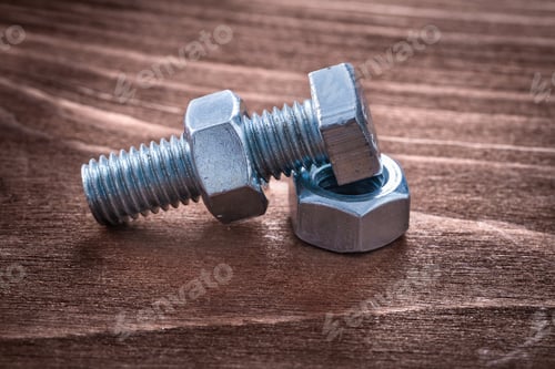 Preview: Threaded Metal Bolt And Some Screw Nuts On Vintage Wooden Board Repairing Concept