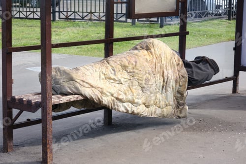 Preview: Homeless Man Sleeps Under A Blanket At A Public Transport Stop