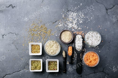 Preview: Variety Of Salt And Seasoning In Wooden Spoons And Ceramic Bowls Over Black Texture Background. Top