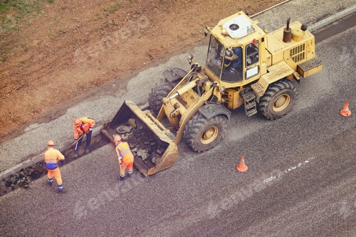 Preview: Workers With Shovels In Their Hands Remove Asphalt From The Road And Putting It In The Bucket Of A