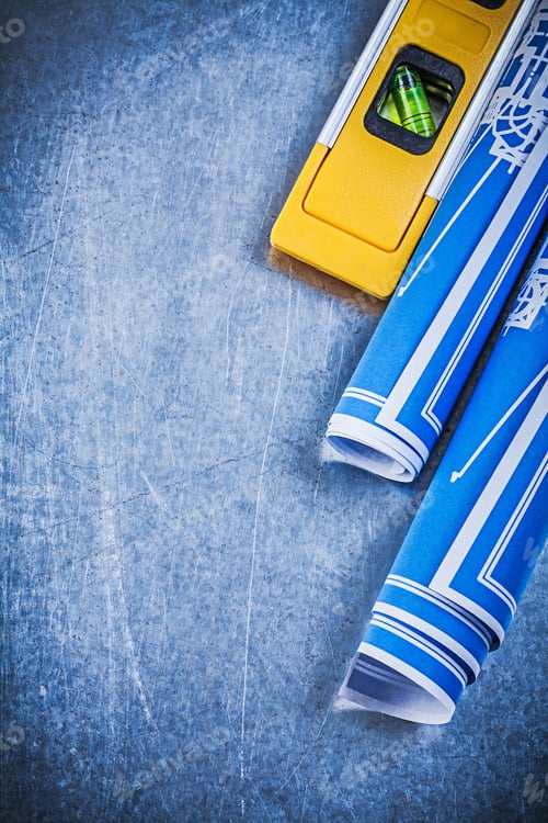 Preview: Rolled Up Blue Blueprints Construction Level On Metallic Background.