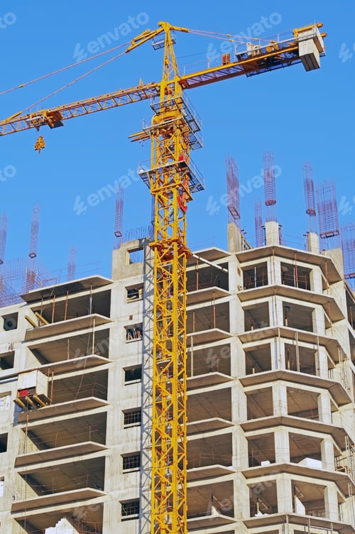 Preview: Building Crane And Building Under Construction Against Evening Blue Sky