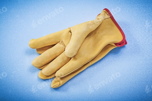 Preview: Pair Of Leather Yellow Protective Gloves On Blue Background Construction Concept.