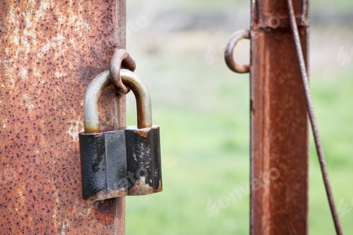 Preview: The Old Padlock Hangs On A Column Of An Iron Rusty Fencing With Green Yard On The Background.