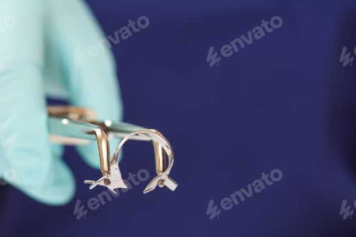 Preview: Close-Up View Of Dentist'S Hand In A Latex Glove With Dental Tongs And Clasp. Shallow Depth Of