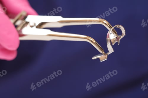 Preview: Close-Up View Of Dentist'S Hand In A Latex Glove With Dental Tongs And Clasp. Shallow Depth Of