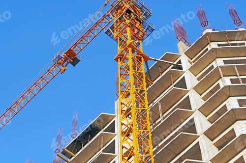 Preview: Building Crane And Building Under Construction Against Evening Blue Sky