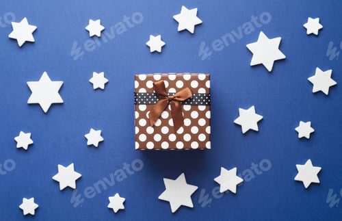 Preview: Christmas Gift Box And White Stars Over Dark Blue Background, Above View