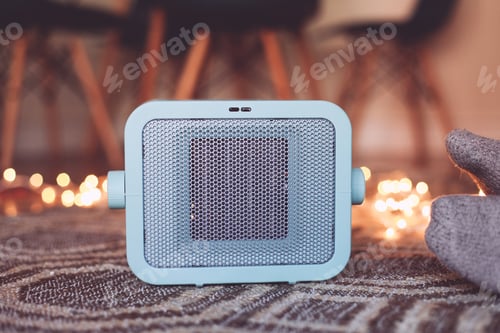 Preview: A Blue Heater On The Carpet In A Cosy Room, Feet In Socks Next To The Heater, Candid Lights