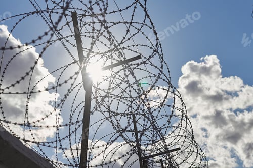 Preview: Round Barbed Wire On Background Of Sun And Dark Clouds, Prison Fence Close Up