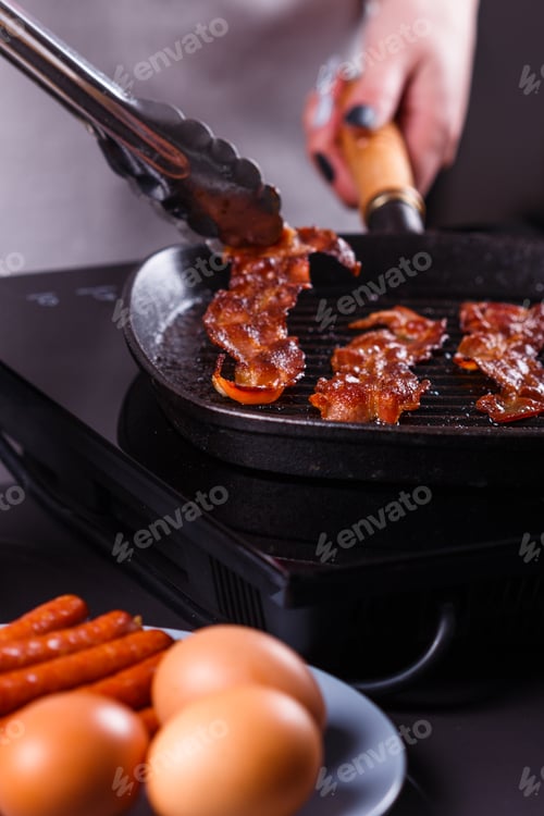 Preview: Young Woman In A Gray Apron Fries Bacon