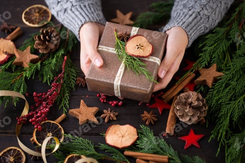 Preview: Person Holding Christmas Gift With Festive Decorations
