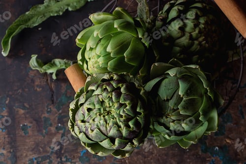 Preview: Fresh Organic Artichokes In A Metal Basket Over A Rustic Wooden Background. Top View