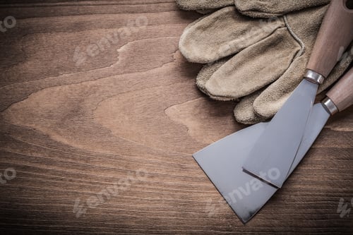Preview: Two Paint Scrapers And Protective Gloves On Wood Board.