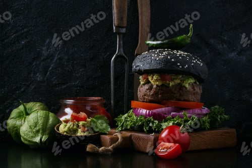 Preview: Home Made Burger With Guacamole Topping And Black Bun Served With Tomatoes And Tomatillos Over A