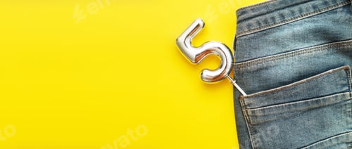 Preview: Number 5 Sticking Out Of The Back Pocket Of Blue Jeans On A Yellow Background