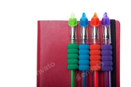 Preview: Red Notebook Diary Or Agenda And Colored Pens Lying On The Top (Isolated On White Background)