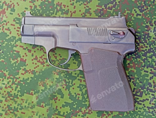Preview: A Small Modern Pistol On Camouflaged Uniform Background