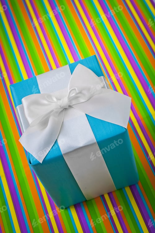 Preview: Blue Gift with White Bow on Colorful Stripes