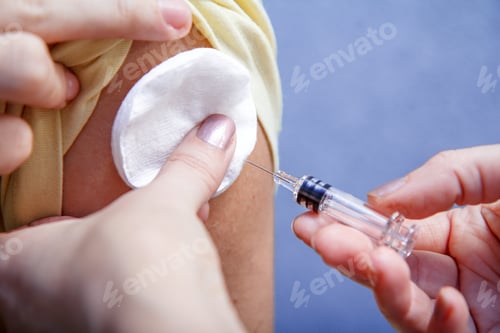 Preview: Hand Of Doctor Holding Syringe For Vaccination To Upper Arm Of Patient For Flu Sickness Prevention